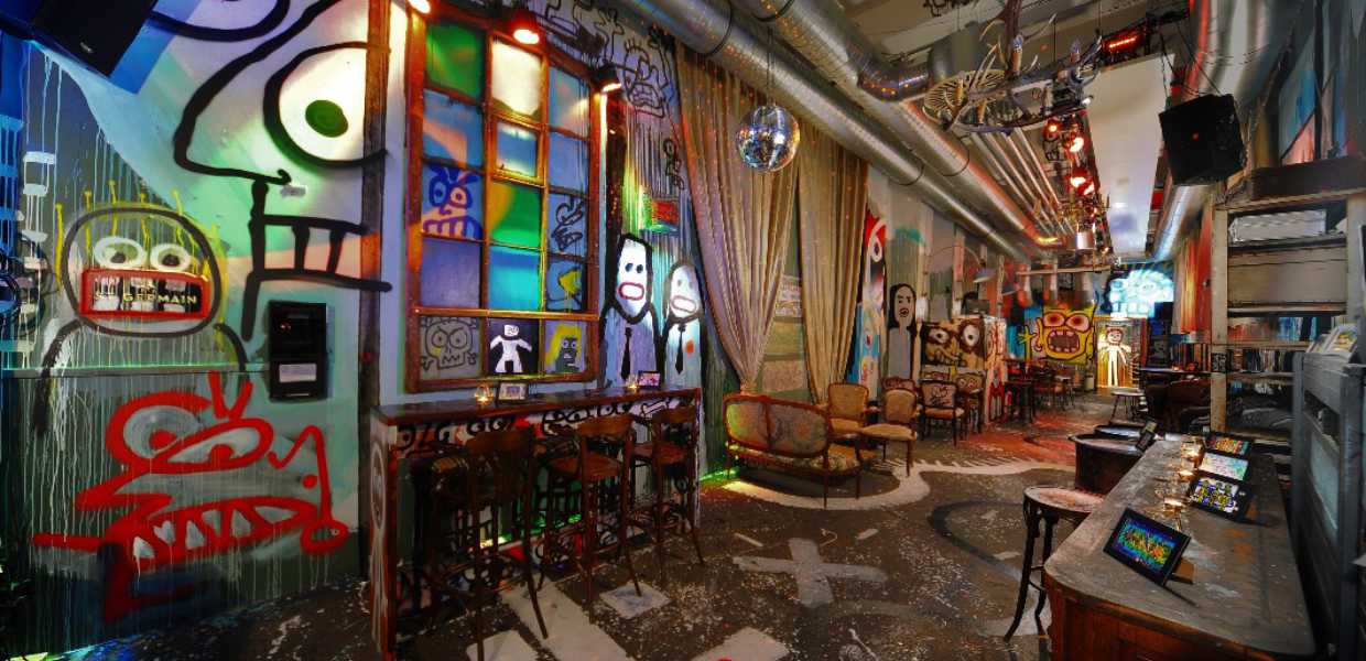 Eventlocation Köln – Panorama der Kunstbar mit Graffiti, Lounge-Möbeln, bunter Fensterkunst und Lichtdesign für Firmenevents.