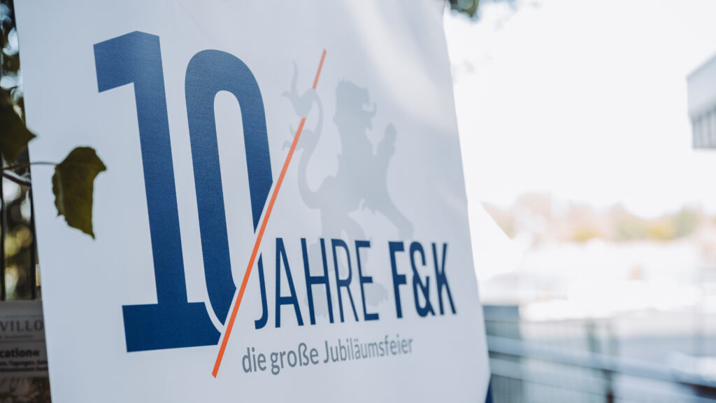 Modern gestaltetes Logo „10 Jahre F&K“ mit Schriftzug und klaren Linien, aufgenommen aus einer nahen Perspektive.