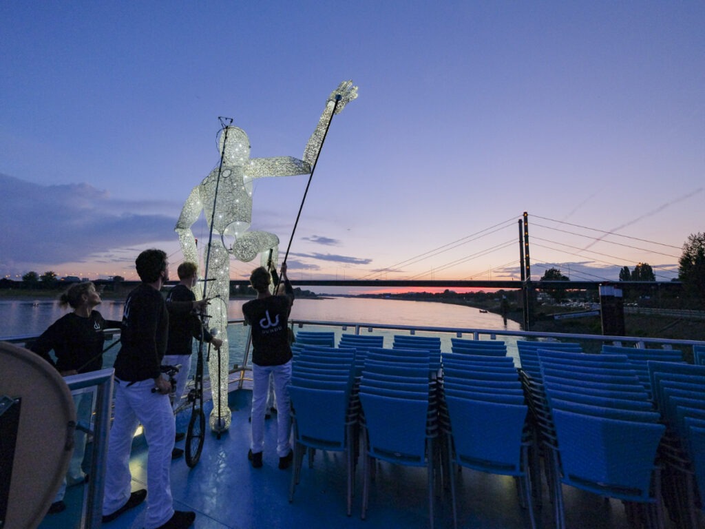 Lichtshow mit leuchtendem Kreis auf einem Eventschiff bei Sonnenuntergang auf dem Rhein.