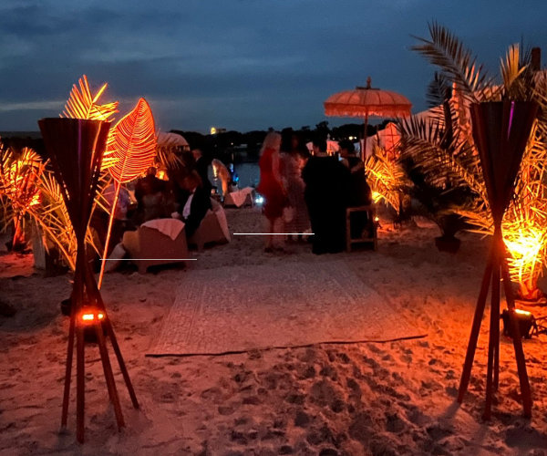 Firmensommerfest in Beach Location mit stimmungsvoller Beleuchtung. Gäste genießen ein emotionales Outdoor Event in sommerlicher Abendatmosphäre