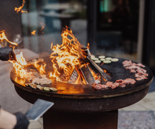BBQ Live Cooking mit offenen Flammen bei einem exklusiven Firmensommerfest in Köln, bei dem frische Speisen direkt vor den Gästen zubereitet werden