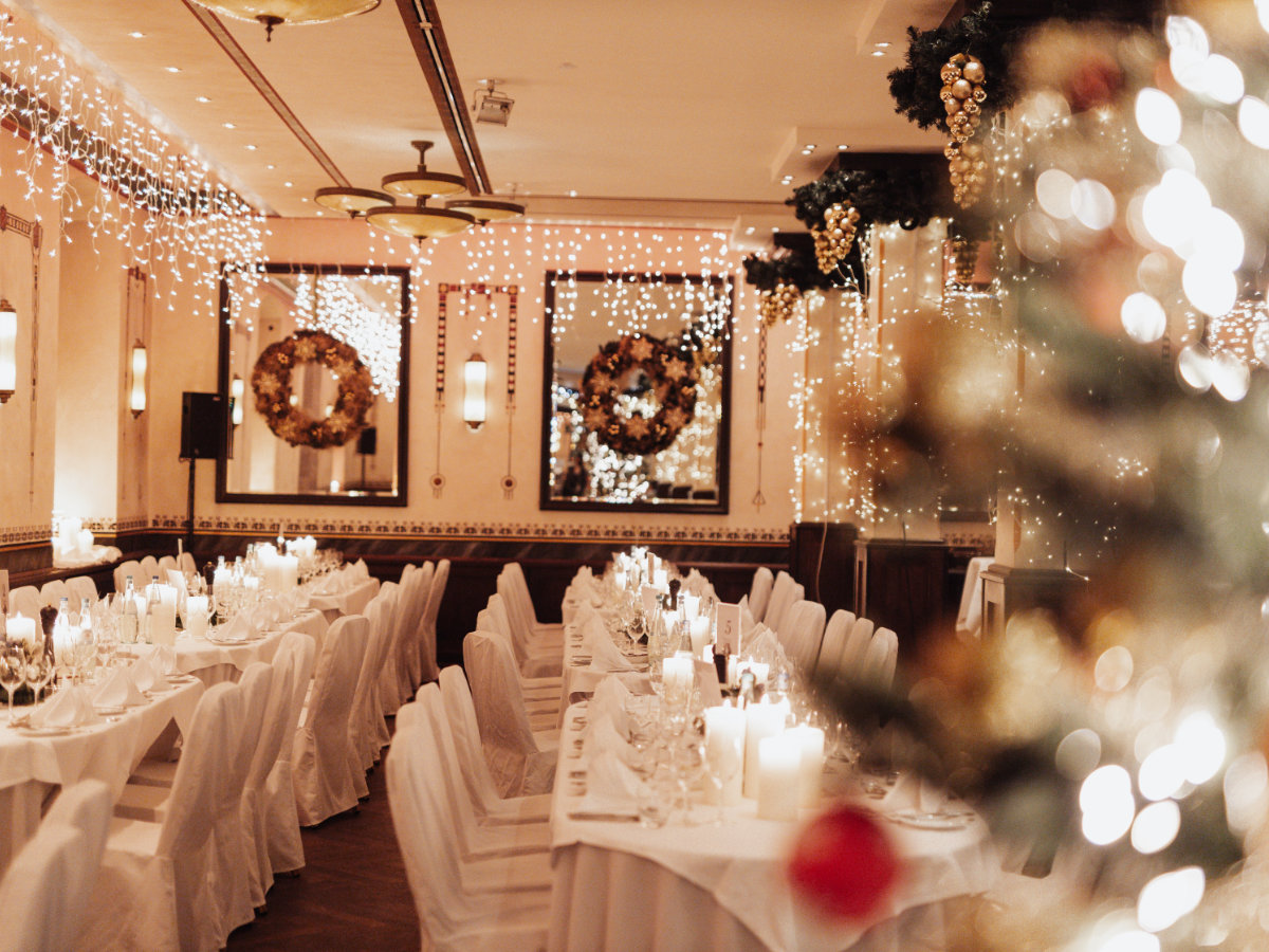 Weihnachtsfeier Firma in festlich dekorierter Eventlocation mit gedeckten Tischen. Das Bild zeigt ein stilvolles Firmenevent mit stimmungsvoller Beleuchtung