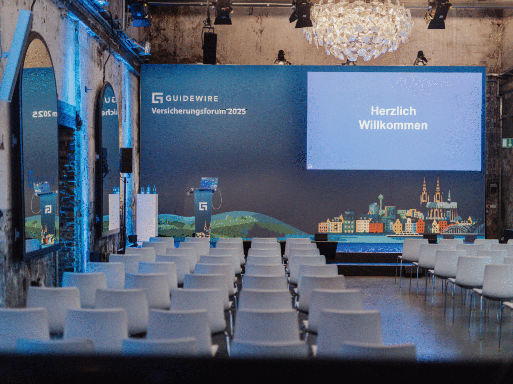 Guidewire Versicherungsforum 2025 im Harbour Club Köln – moderne Tagungslocation mit Bühne und Sitzreihen.